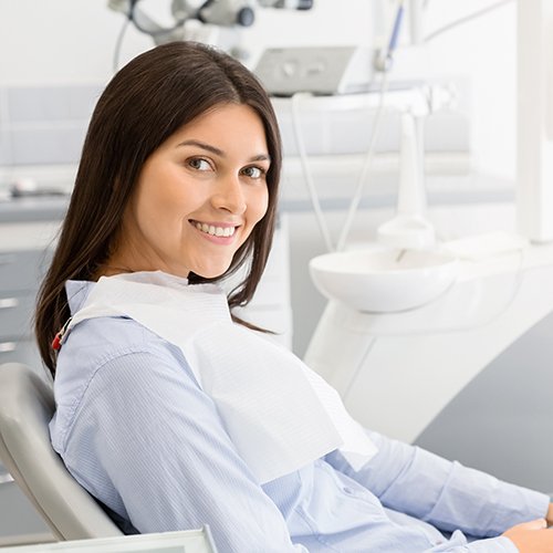 Woman sitting in chair at periodontist’s office and smiling