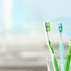 Three toothbrushes in a clear plastic cup