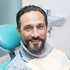 Bearded male periodontal patient sitting in chair and smiling